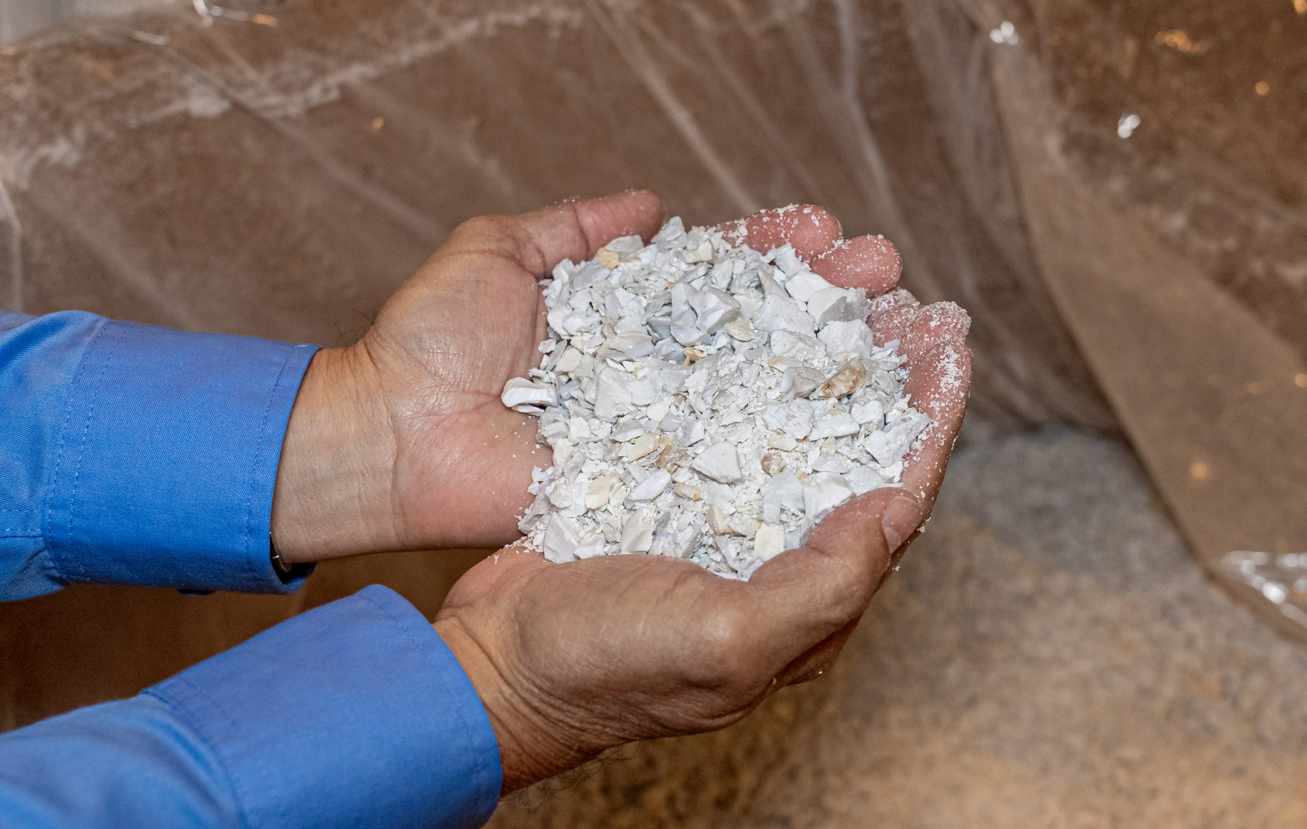 Eine Person hält zerkleinertes, weißes Recyclingmaterial in den Händen.