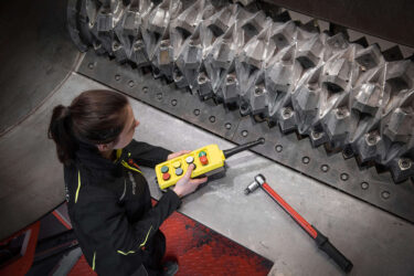 Servicetechnikerin steht mit Remote Control im Schneidraum des WEIMA WKS 1800 Shredders