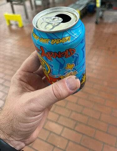 In einer männlichen Hand befindet sich einen bunte Bierdose der Saint Arnold Brauerei.