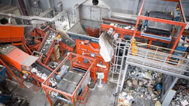 Luftansicht von einem orangenen Shredder der Siedlungsabfälle in einem Recyclingunternehmen in Südkorea zerkleinert
