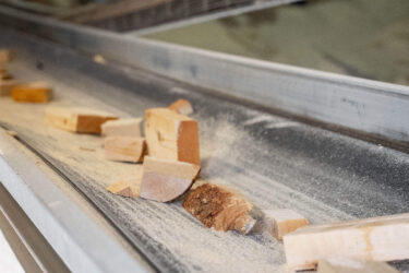 Auf einem Förderband befinden sich Holzreste.