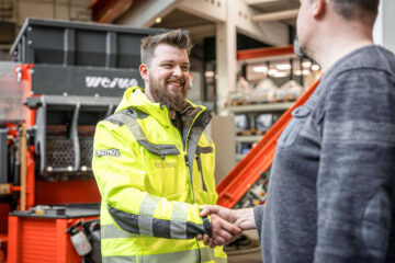 WEIMA Service Techniker Mitarbeiter mit gelber Warnjacke begrüßt Kunden
