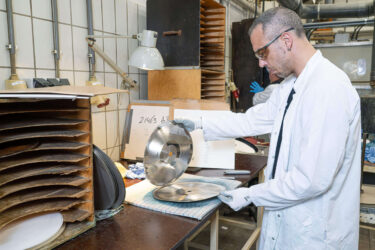Ein Record Industry Mitarbeiter öffnet eine metallische Negativform für die Schallplatten Herstellung