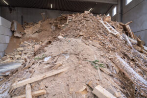 Großer Haufen aus Holzresten, Brettern, Ästen in einer Lagerhalle des Brennholzwerks Trier.